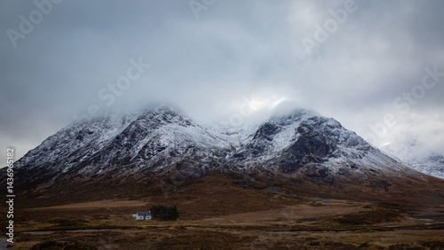A breathtaking panoramic view of the Scottish Highlands, featuring snow-capped mountains rising above vast open moorland and rugged terrain.