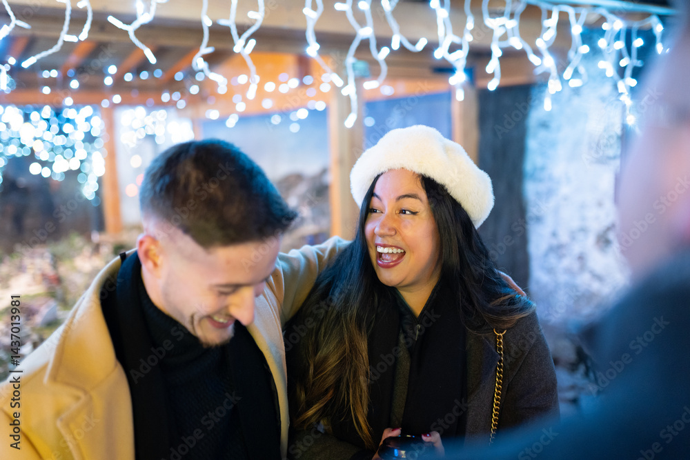 Fototapeta premium Happy couple laughing together at christmas market, enjoying festive atmosphere