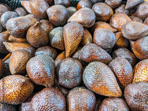A detailed close-up photograph showcases a dense aggregation of snake fruit. The fruits characteristic brown, scaly integument and irregular shapes contribute to a visually complex.
