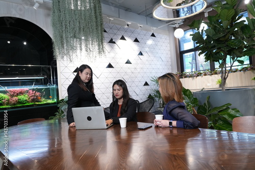 Obraz na płótnie A group of three Asian female marketing colleagues discussing online sales and planning in a company conference room. w salonie