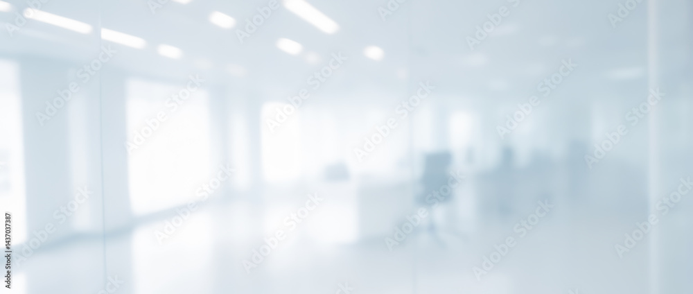 Blurred view of a bright white office space with large windows and columns. Blurred view of a bright white office space with large windows and columns.
