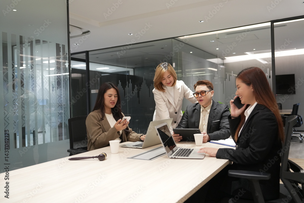A group of lawyers sit in a meeting to discuss and find a solution, and an Asian female lawyer holds a smartphone and talks to her clients in a meeting room at a law office.