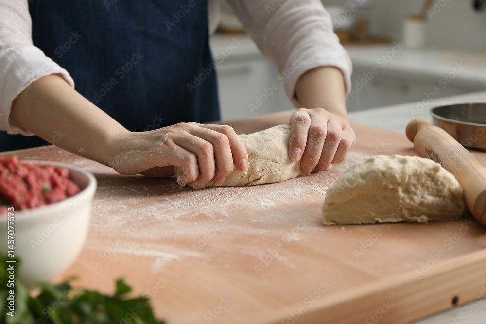 Making khinkali. Woman kneading dough at table in kitchen, closeup Making khinkali. Woman kneading dough at table in kitchen, closeup