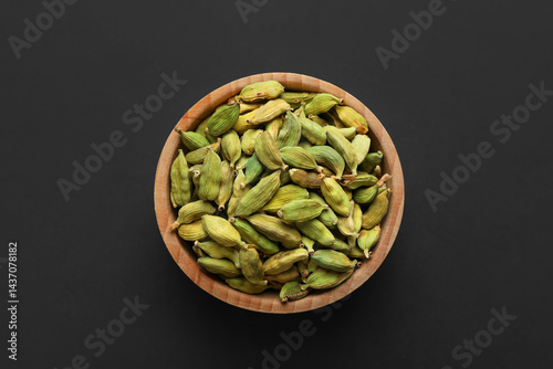 Dry cardamon seeds in bowl on dark table, top view