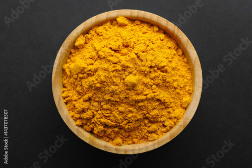 Fototapeta Naklejka Na Ścianę i Meble -  Turmeric powder in bowl on black background, top view. Aromatic spice