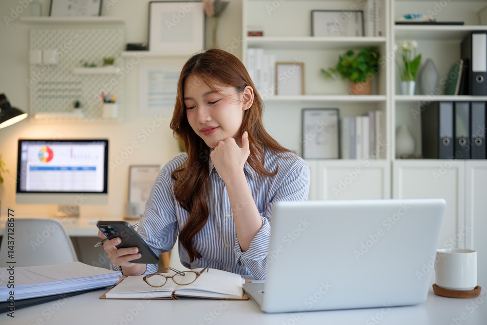 Smiling young businesswoman using smartphone at her home office desk. Smiling young businesswoman using smartphone at her home office desk.