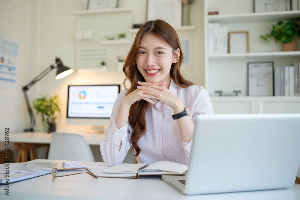Confident female entrepreneur smiling at camera while working in modern home office. Confident female entrepreneur smiling at camera while working in modern home office.