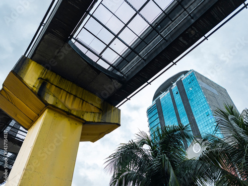 Urban railway with yellow pillar and tropical city background