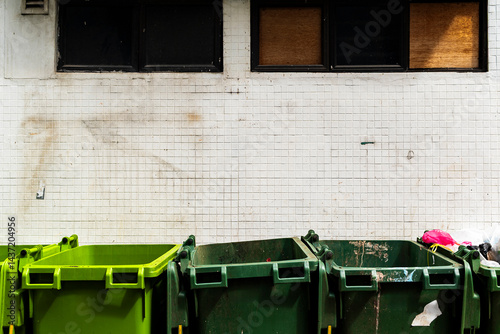 Trash bins lined up against dirty tiled wall
