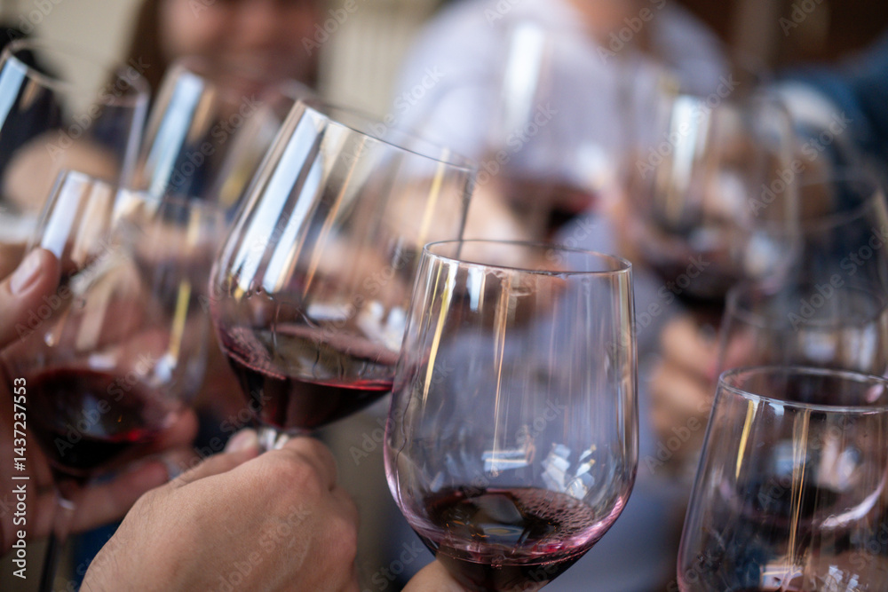 A group of people raise a toast with glasses of red wine A group of people raise a toast with glasses of red wine