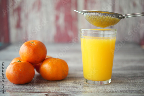 Freshly squeezed orange juice being strained into a glass photo