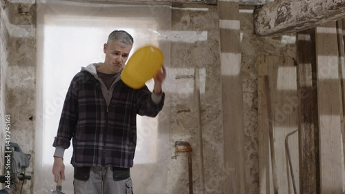Construction builder worker on site wearing safety helmet, tapping hard hat with fist and hammer, showing confidence and protection, emphasizing workplace safety and personal protective equipment, PPE