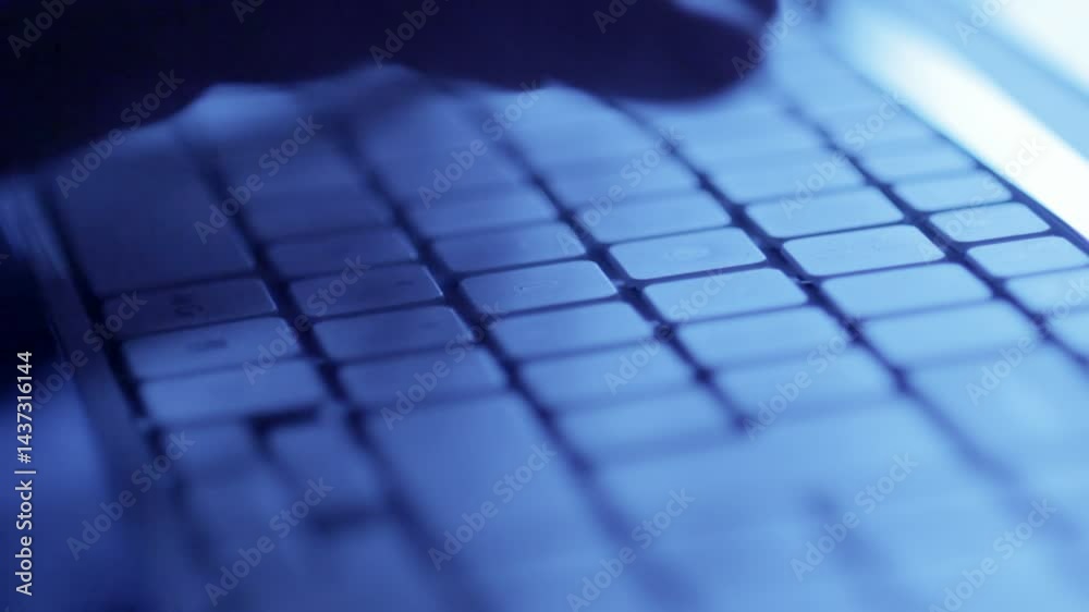 Silhouette of hands typing on a keyboard in the dark