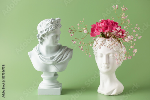 Creative art concept plaster head ancient sculpture with hair fresh flowers gypsophila and hydrangea on green background. Copy space