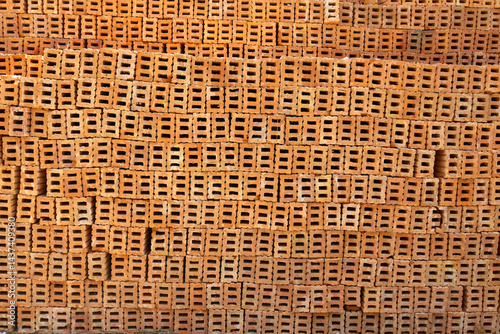 Orange bricks for construction are stacked like a wall.