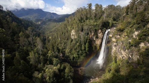 Majestic waterfall cascading down lush green cliffs, rainbow visible, mountains in background