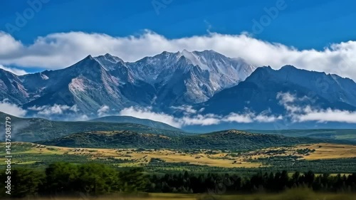 Majestic mountain range with dynamic cloud movement over verdant landscape