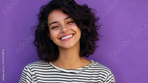 Joyful woman smiling and laughing against vibrant purple background