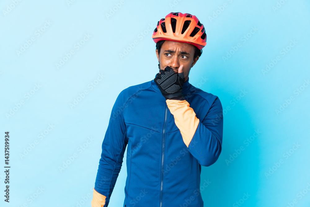 Fototapeta premium Young cyclist man with braids over isolated background having doubts and with confuse face expression