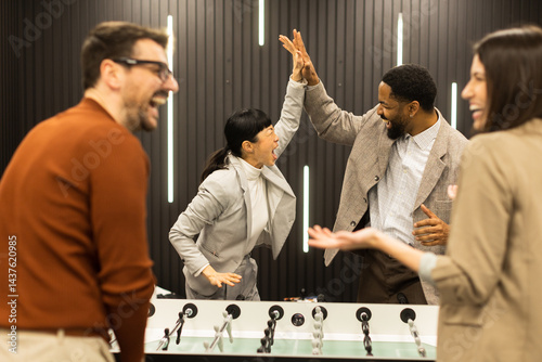 Joyful celebration among friends during a foosball game in a stylish indoor setting