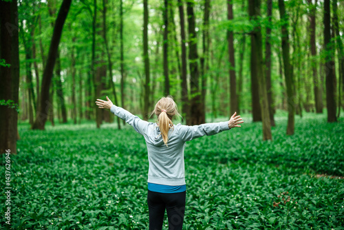 Obraz na płótnie Woman athlete celebrating freedom with arms wide open in nature, symbol of relaxation and mental wellbeing. Forest bathing w salonie