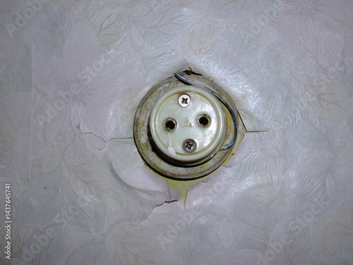Electrical outlet with visible texture and surrounding damage in indoor setting captured in residential area during daylight