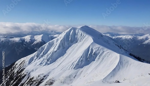 A snowy mountain peak under a clear blue sky with clouds in the distance on a sunny winter day