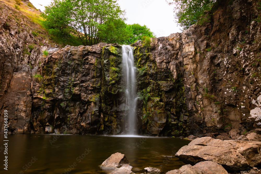 Flowing creek water over the rocks of a waterfall in the summer.