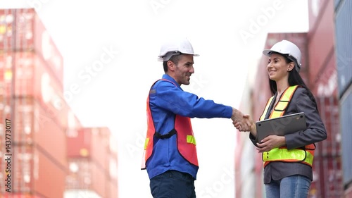 A female speaker gives a safety briefing at a shipping container yard, while a male worker listens attentively in protective gear.