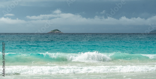 Obraz na płótnie Tropical turquoise ocean waves breaking on sandy beach in Seychelles with distant island on horizon w salonie