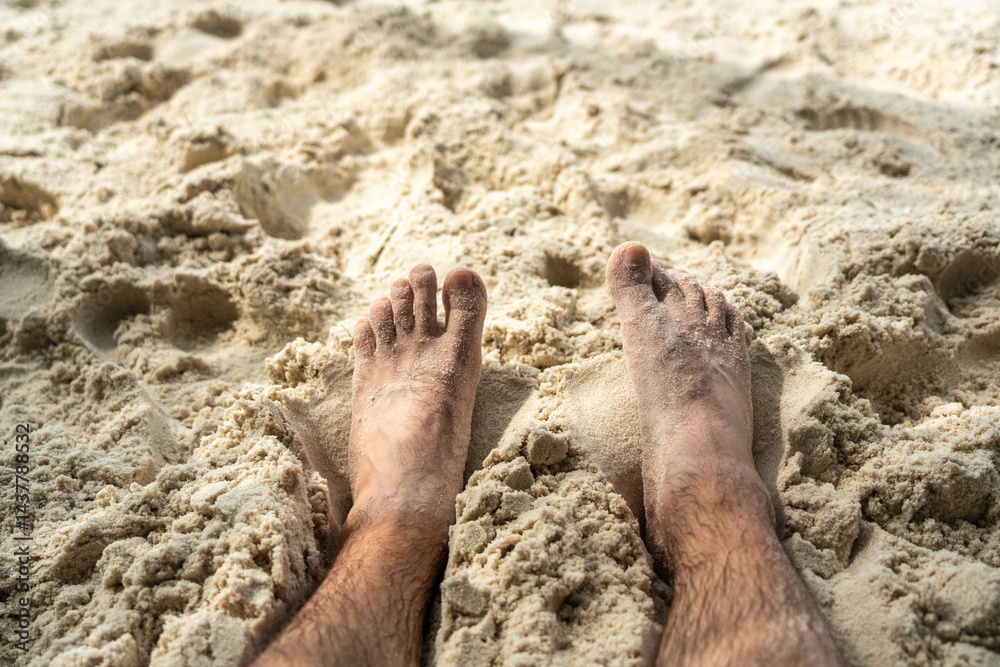 Bare feet resting in warm sand on tropical beach, symbolizing summer relaxation, freedom