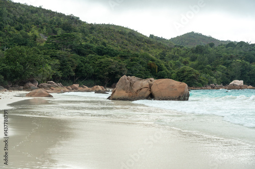 Obraz na płótnie Tropical beach on Praslin island, Seychelles, with turquoise ocean waves, lush jungle hills w salonie