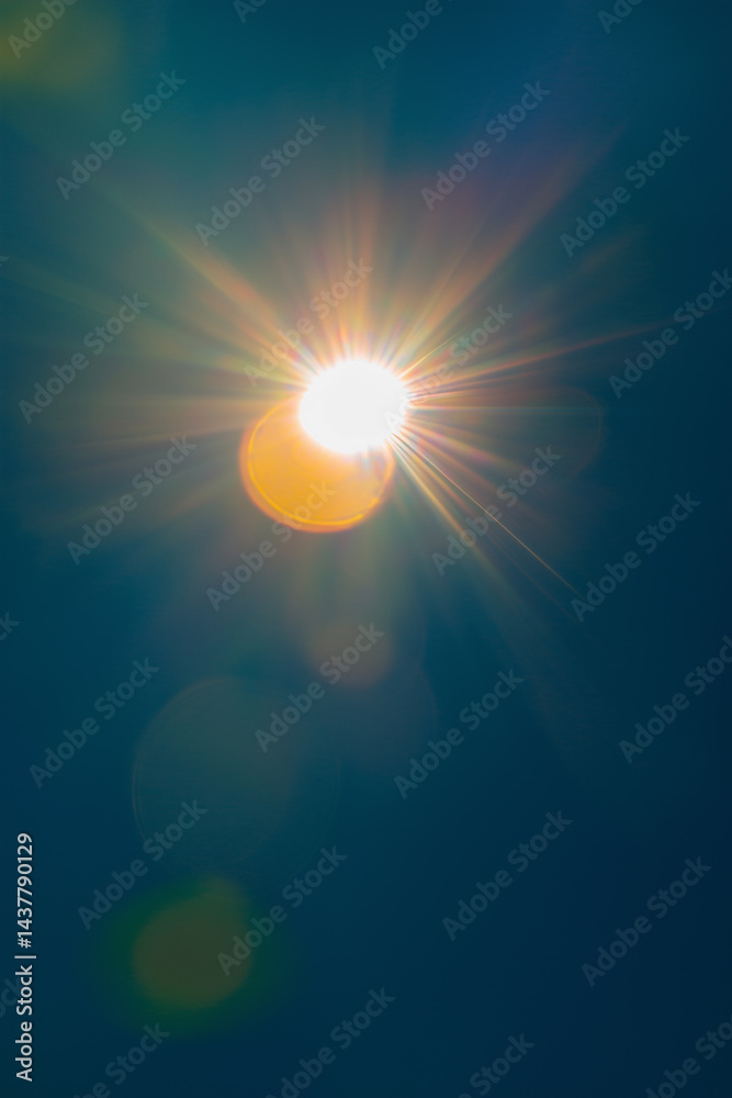 Obraz premium Bright sunlight with colorful lens flare against clear blue sky