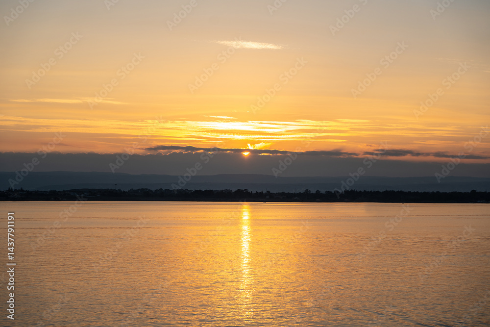 Sunset over the ocean, with the sun low on the horizon, contrast between sky and sea