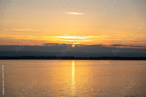 Obraz na płótnie Sunset over the ocean, with the sun low on the horizon, contrast between sky and sea w salonie