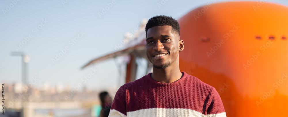 African american man smiles on a sunny city day. Concept of happiness, relaxation, travel and urban lifestyle