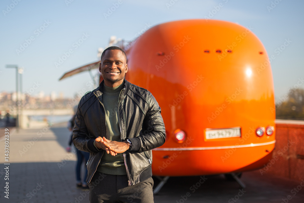 African american man posing in front of a colorful food truck. Concept of travel, style, leisure and confidence
