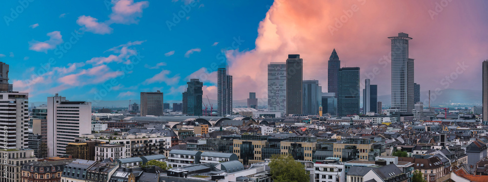 Aerial view of Frankfurt, Germany, featuring modern skyscrapers, traditional architecture, and the Hauptbahnhof under a vibrant sunset sky.