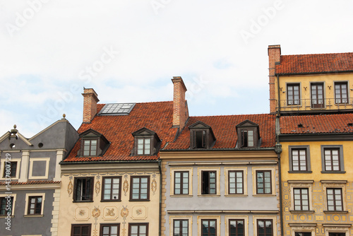 Traditional European architecture with vibrant facades, red clay roof tiles, dormer windows, and ornate exterior wall decorations in a picturesque old town setting