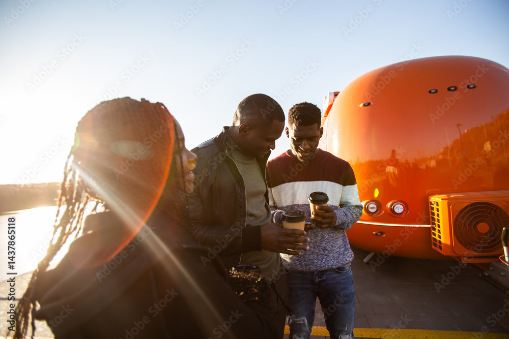 African american friends looking smartphone while standing by river. Concept of technology, friendship, real life connection.