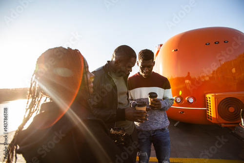 Obraz na płótnie African american friends looking smartphone while standing by river. Concept of technology, friendship, real life connection. w salonie