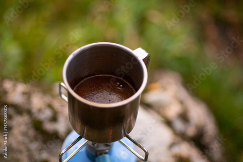 iron tourist mug with hot coffee on the gas burner in outdoor
