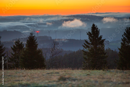 a windmills generator in the mountains covered with fog at sunrise time