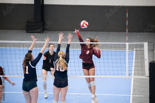 Female volleyball player rolling the ball over a double block