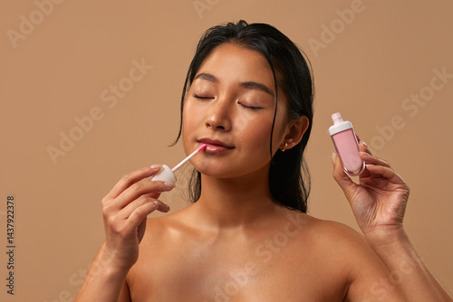Wallpaper Mural Asian woman with lip gloss on a beige background Torontodigital.ca
