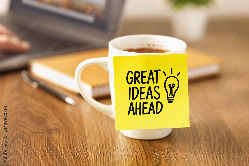Coffee cup with yellow sticky note showing great ideas ahead message on wooden desk workplace motivation inspiration creativity productivity goal planning startup concept