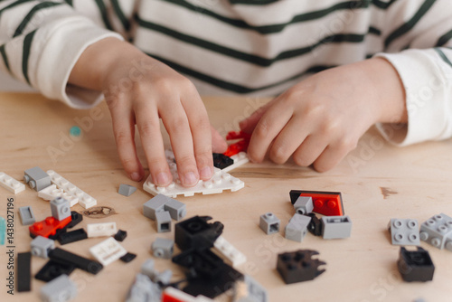 A child is playing with a plastic construction kit. close-up of a child's hands with elements of a plastic construction kit