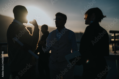 A group of diverse business people engages in brainstorming on a high rise balcony at sunset, fostering creativity and collaboration. The silhouette adds an inspiring and contemplative ambiance.