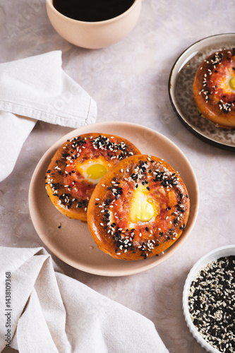 Obraz na płótnie Egg with tomato and sesame seeds baked in bagels on a plate on the table vertical view w salonie