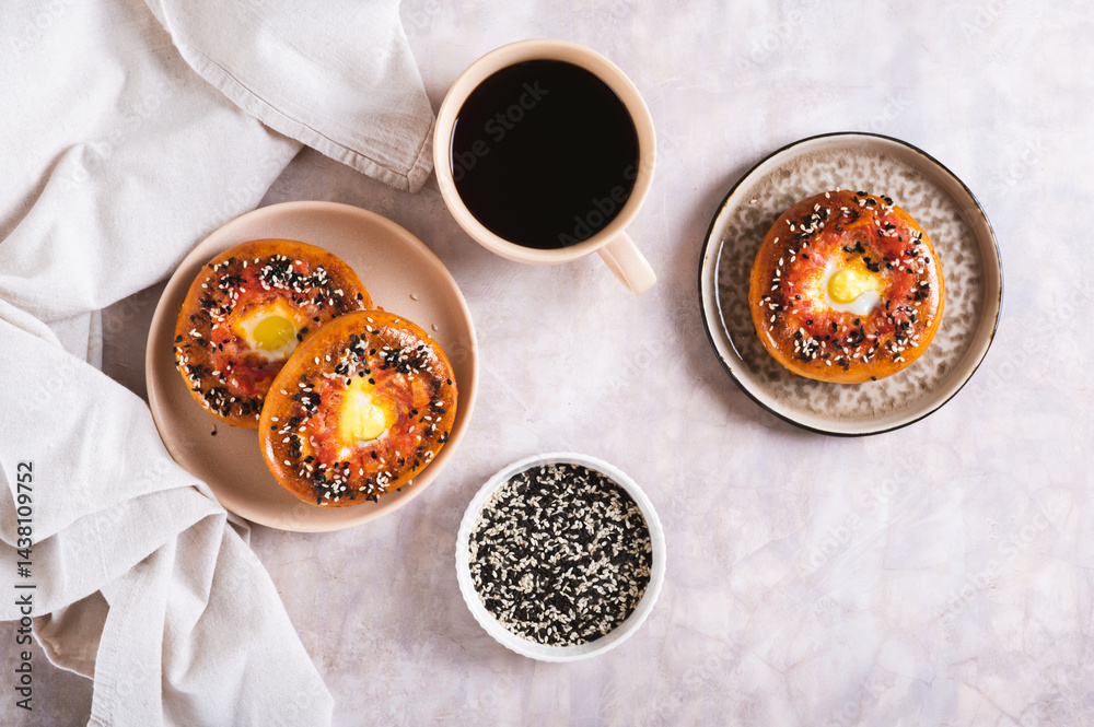 Baked bagels with tomato and quail egg on a plate on the table top view